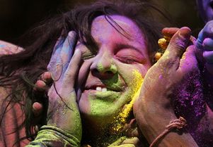 People apply coloured powder to a woman's face as they celebrate Holi in Ahmedabad.
