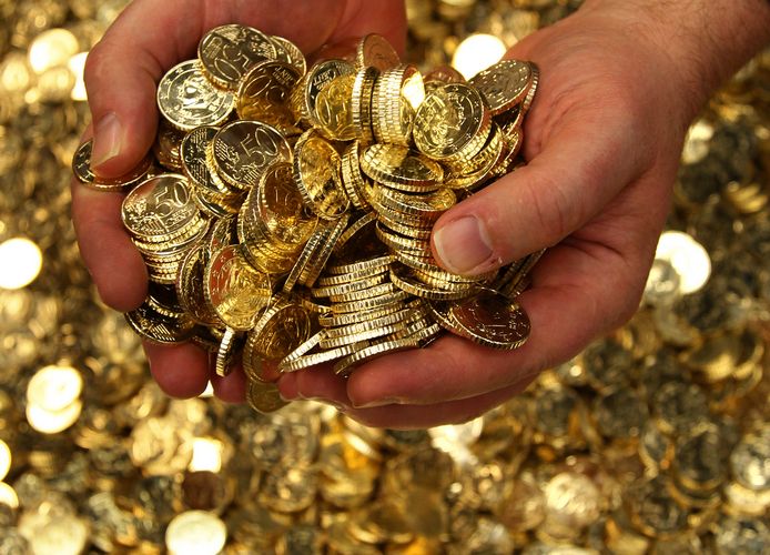 An employee at Belgium's Royal Mint scoops up a handful of fifty euro cent coins in Brussels 