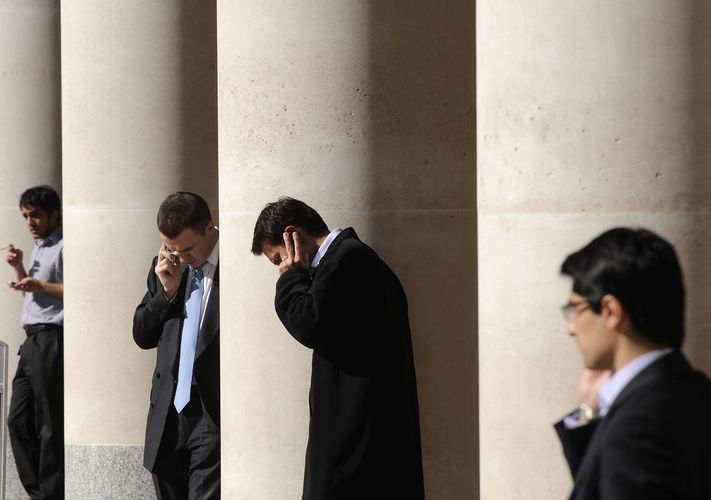 City workers make phone calls outside the LSE in Paternoster Square in the City of London