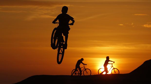 Cyclists perform stunts during sunset