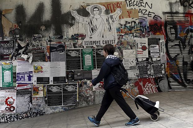 A pedestrian walks past a drawing of Greek Prime Minister Alexis Tsipras