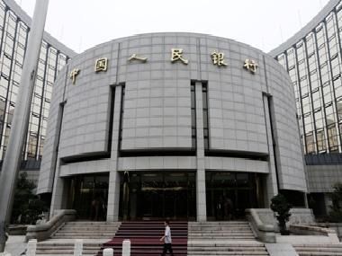 A staff member walks in front of the headquarters of the People's Bank of China (PBOC), the central bank, in Beijing