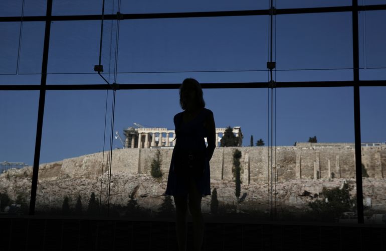 A woman looks at exhibits on display in the Parthenon hall at the Acropolis museum
