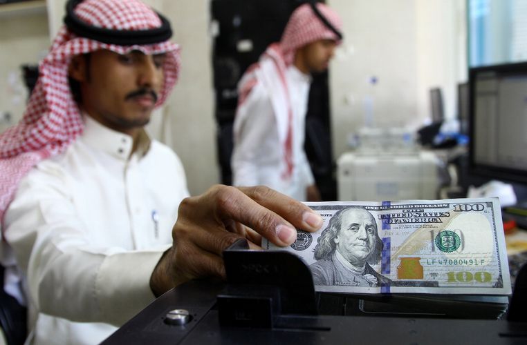 A Saudi money changer counts US banknotes at a currency exchange shop in Riyadh