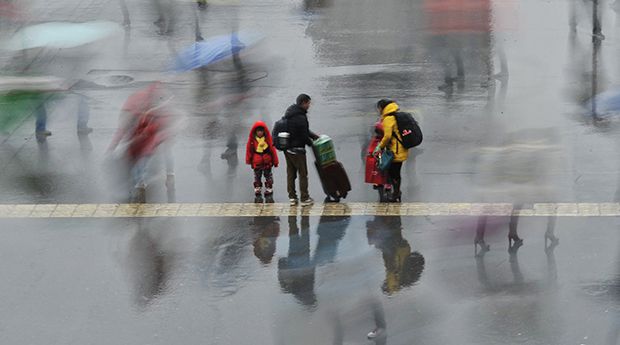 A long exposure photo shows a family standing under the rain outside a railway station in Hefei