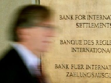 A man walks past a sign in front of the Bank For International Settlements (BIS) in Basel