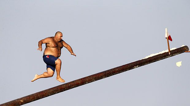 A man runs up the “gostra”, a pole covered in grease