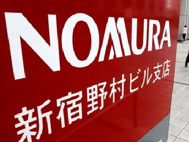 A man walks next to a sign for Nomura Securities in Tokyo