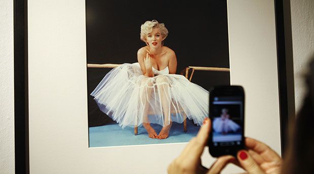 A woman takes picture of a framed Marilyn Monroe photo at gallery in Warsaw