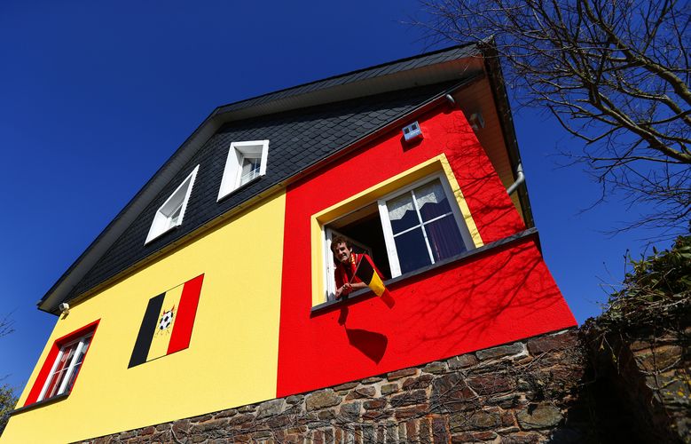 Wilfried Thelen poses at a window of his house that is painted in black, yellow and red, the colours of Belgium's national flag,