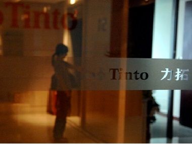 A woman is reflected in a glass door of the Rio Tinto Limited Shanghai Representative Office