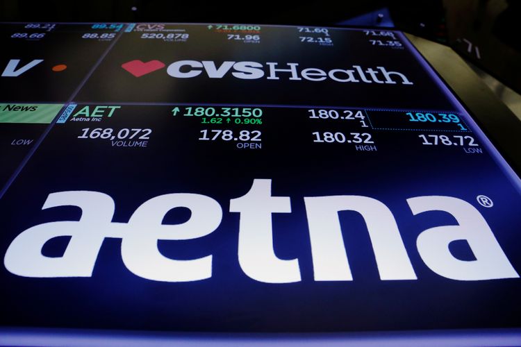 Logos of CVS and Aetna are displayed on a monitor above the floor of the New York Stock Exchange