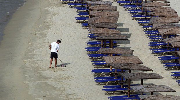 A boy cleans a beach on the Cycladic island of Andros early in the morning