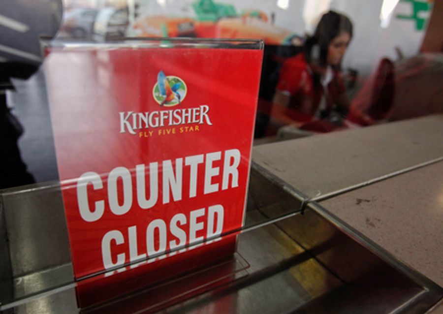 An employee of Kingfisher Airlines works next to a counter closed sign at the carrier’s booking of