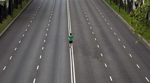 A runner warms up in the middle of an empty avenue
