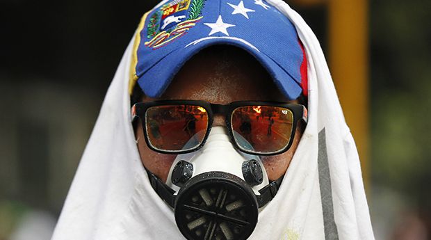 An anti-government protester wears a gas mask during riots at Altamira square in Caracas