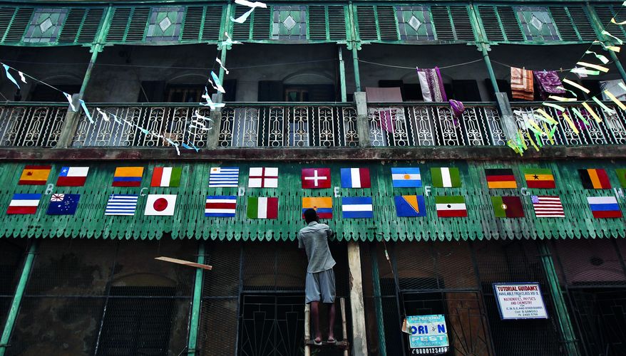 A man paints the exterior of a house with the national flags of 2014 World Cup teams in Kolkata