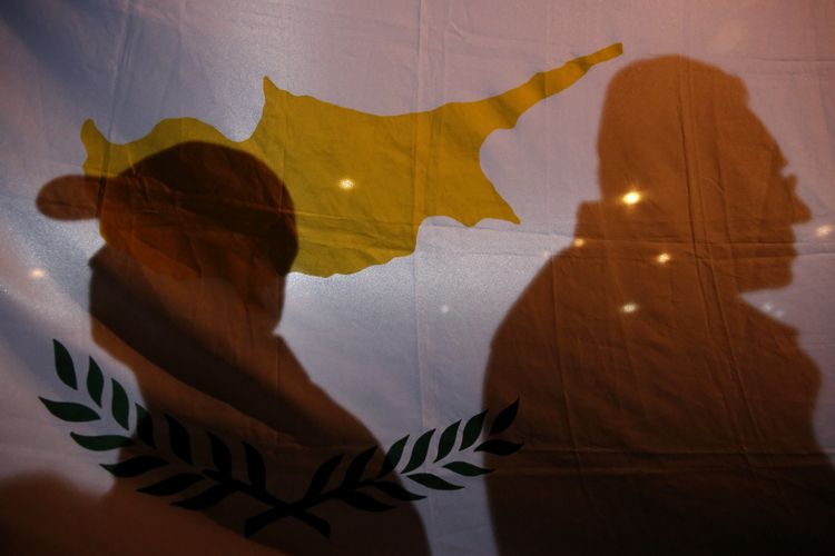 Protesters cast their shadows on a Cypriot flag during an anti-bailout rally outside the presidential palace in Nicosia 