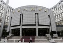 A staff member walks in front of the headquarters of the People's Bank of China (PBOC), the central bank, in Beijing