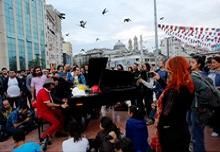 Pianist Davide Martello of Germany (red) is surrounded by anti-government protesters as he performs at Taksim square in central Istanbul 
