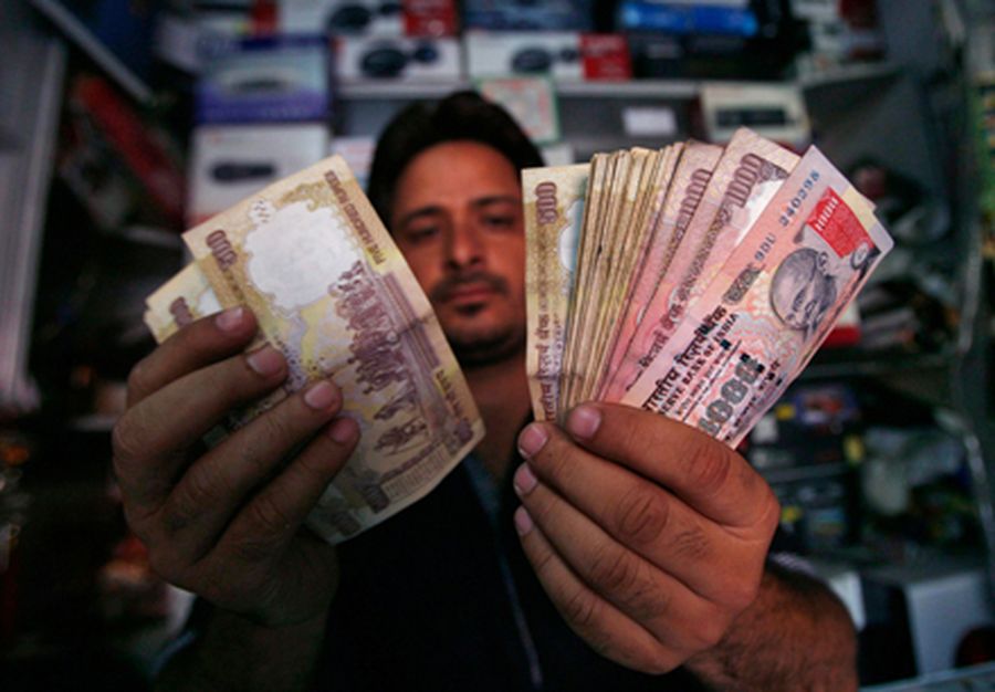 A shopkeeper poses for a picture as he counts Indian currency notes at his shop in Jammu. 