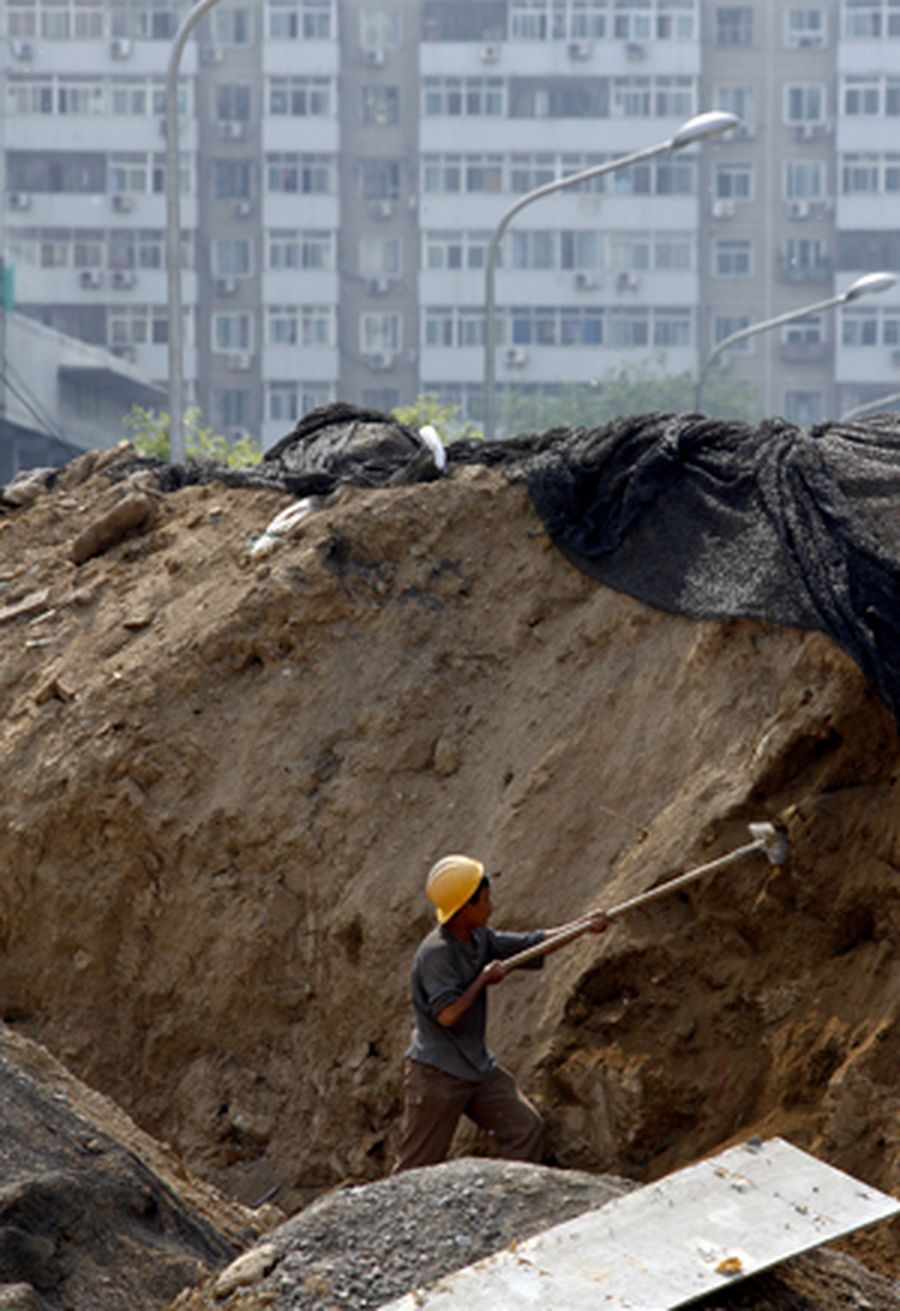 A migrant worker uses a shovel as he works in a construction site in central Beijing.