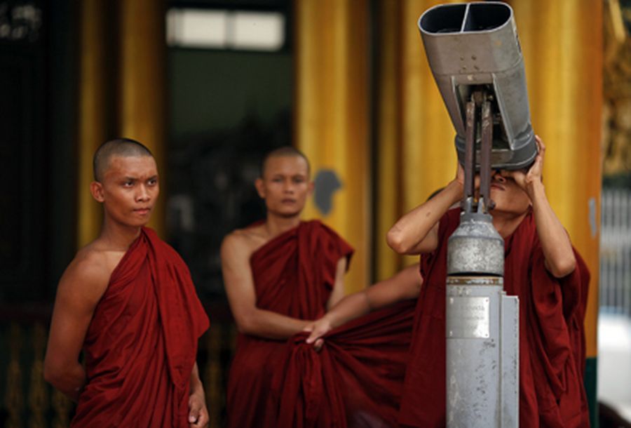 A Buddhist monk looks through the binoculars at Shwedagon Pagoda in Yangon 