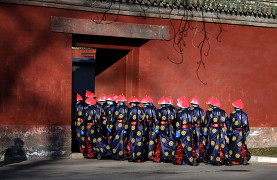 Actors wearing traditional costumes march through a small door as they prepare to take part in an an
