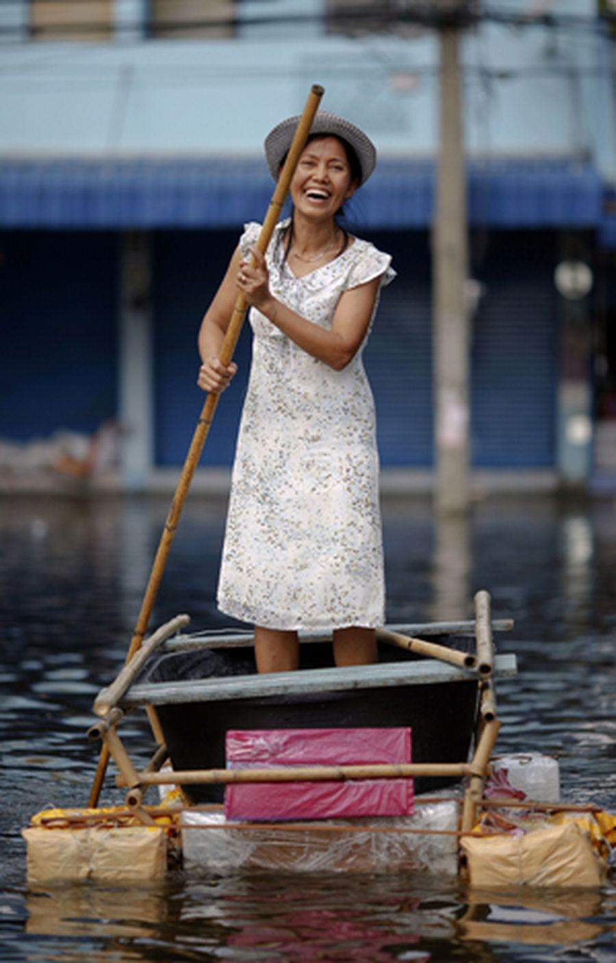 A woman smiles as she manoeuvres a makeshift raft through a newly flooded neighborhood in Bangkok.
