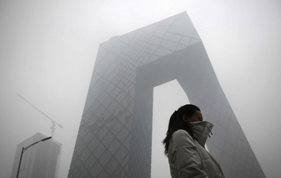 A woman walks past the new China Central Television (CCTV) building amid heavy fog in Beijing.