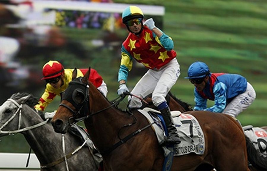 Jockey Douglas Whyte (C) riding Ambitious Dragon celebrates as he crosses the finish line to win the 2,000-metre Audemars Piguet QEII Cup Group One race at Shatin racetrack in Hong Kong.
