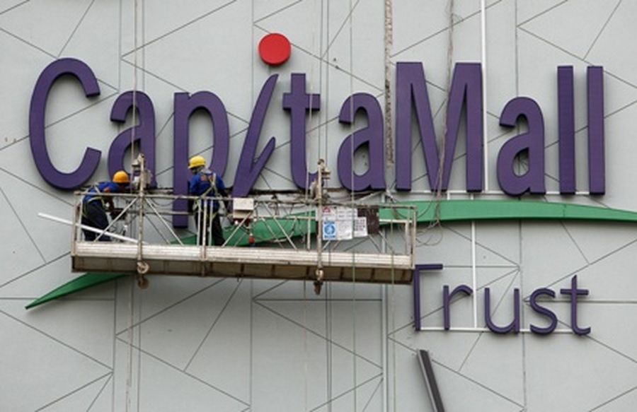 Workers install CapitaMall Trust signage on the facade of a new shopping mall in Singapore. 