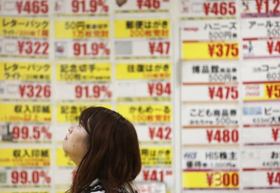 A woman walks past a ticket shop displaying prices in Tokyo. 