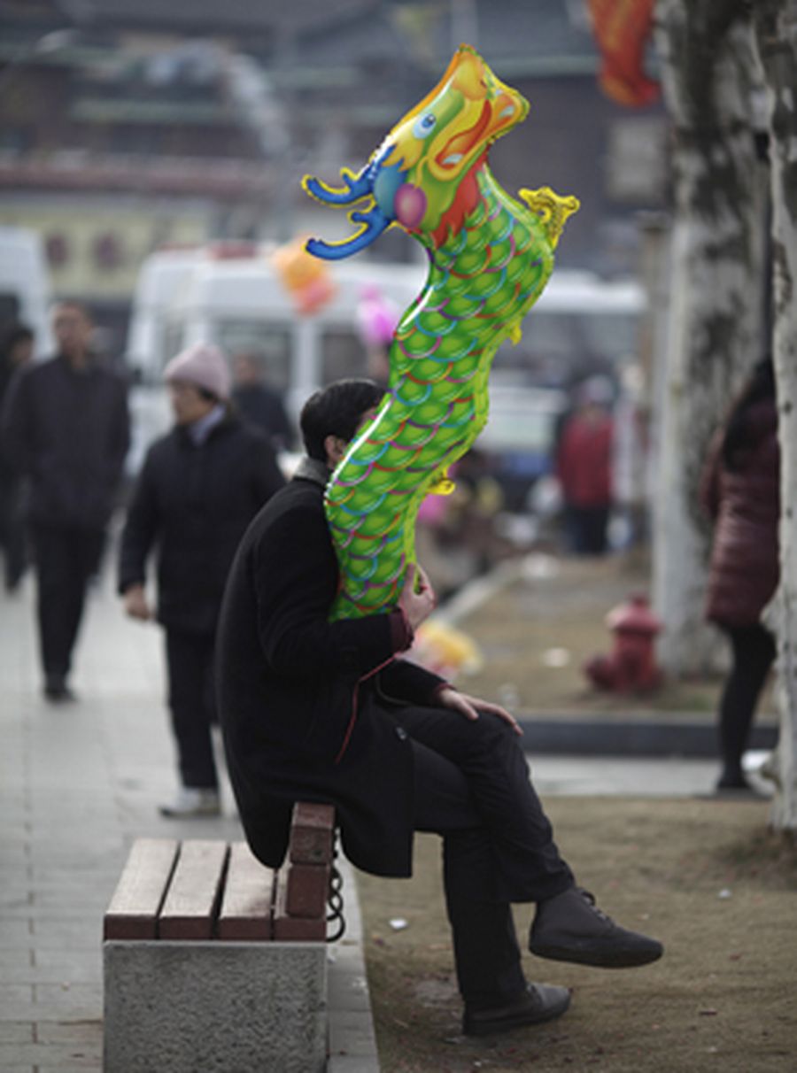 A man holds a dragon balloon outside Longhua Buddhist Temple on the first day of the Chinese Lunar N
