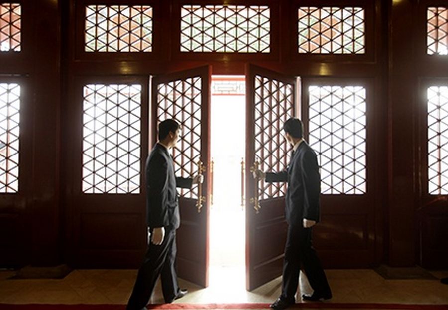 Waiters open a Chinese traditional red door inside a luxurious furniture museum in Beijing.